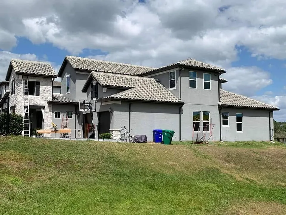 Gray stucco two story barrel tile roof black gutters wide, Sanford